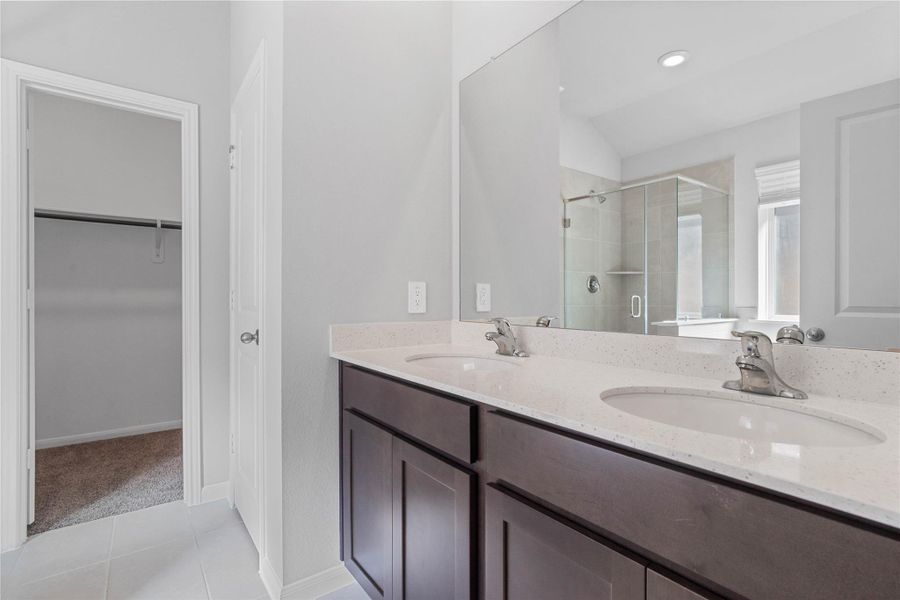 A bright and functional primary bath offering dual sinks for busy mornings, a large mirror, soaking tub, and a modern glass-enclosed shower, creating a serene and efficient space.