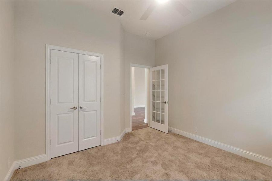 Unfurnished bedroom featuring carpet floors, baseboards, a closet, french doors, and a ceiling fan