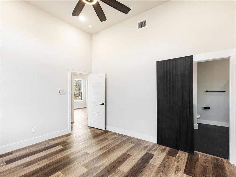Empty room featuring a towering ceiling, wood finished floors, and ceiling fan Empty room featuring a towering ceiling, wood finished floors, and ceiling fan