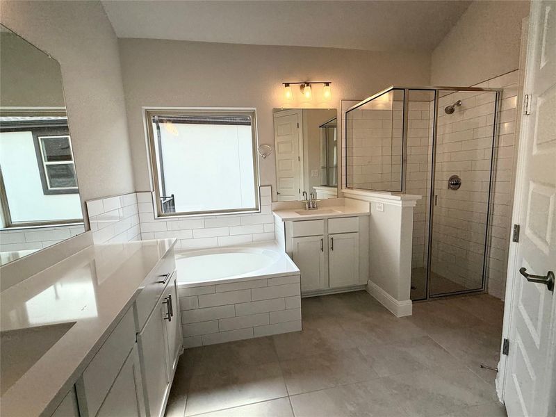 Bathroom featuring two vanities, a stall shower, a garden tub, and tile patterned flooring Bathroom featuring two vanities, a stall shower, a garden tub, and tile patterned flooring