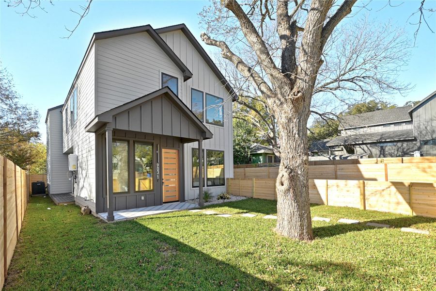 Rear view of property with central AC unit, a lawn, board and batten siding, and a fenced backyard