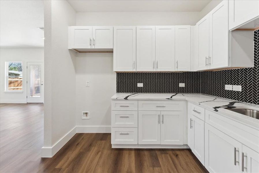 Kitchen featuring backsplash, white cabinets, wood-style floors, and quartz counter tops