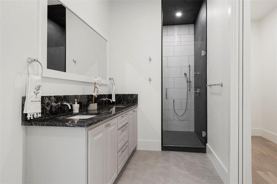 Full bathroom featuring a shower stall, double vanity, and light tile patterned flooring Full bathroom featuring a shower stall, double vanity, and light tile patterned flooring