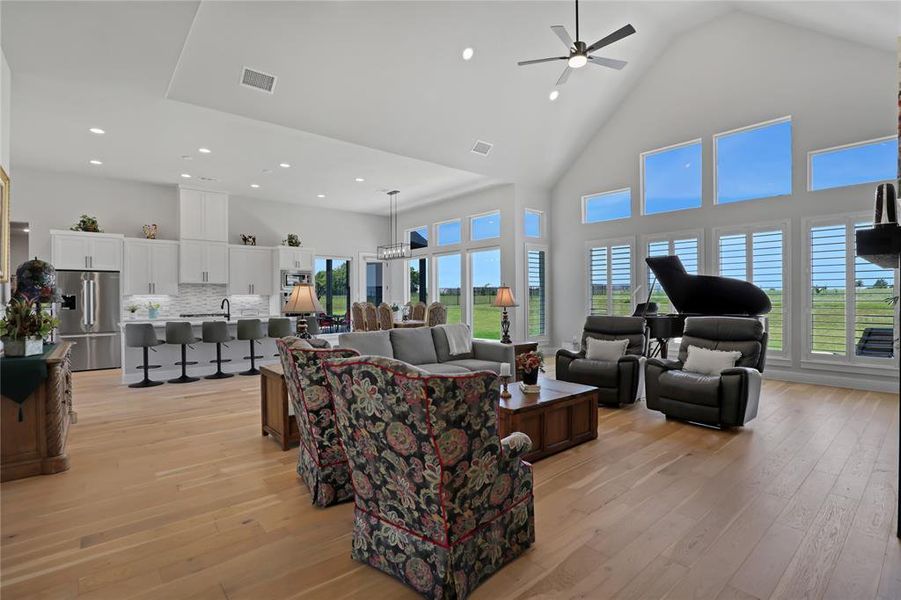 Living room featuring high vaulted ceiling, light wood-style floors, a ceiling fan, and recessed lighting Living room featuring high vaulted ceiling, light wood-style floors, a ceiling fan, and recessed lighting