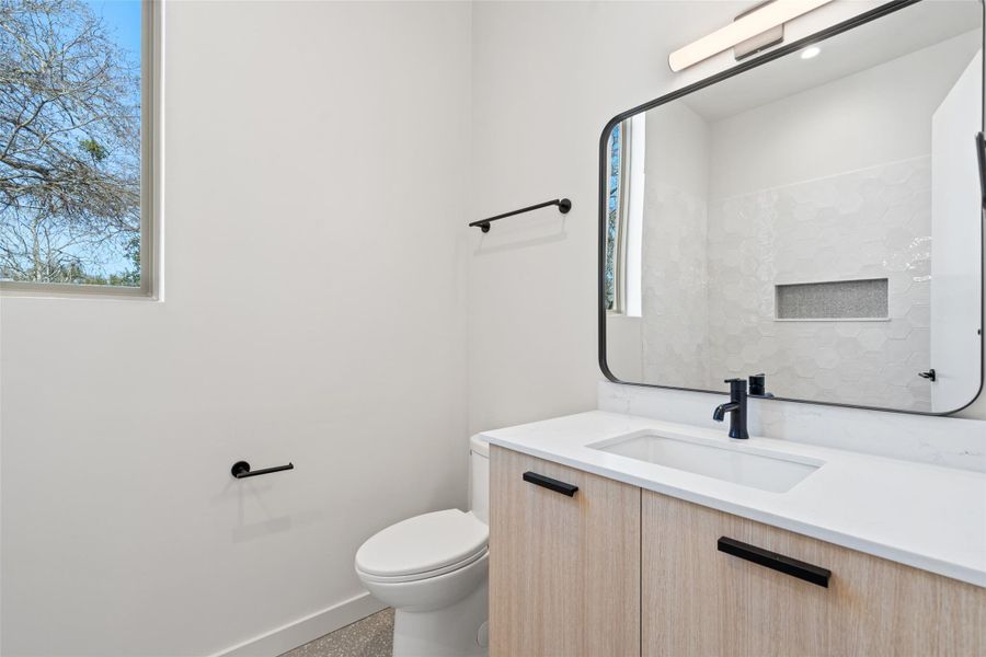 Half bath featuring baseboards, vanity, and toilet