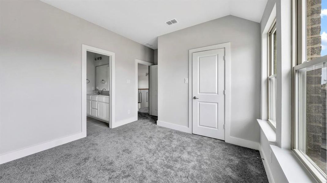 Unfurnished bedroom with carpet flooring, ensuite bathroom, and lofted ceiling