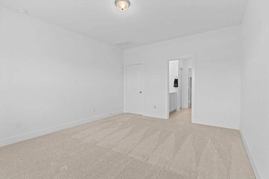 Another angle of the spacious primary bedroom highlights its clean lines, generous layout, and direct access to the luxurious en-suite bath—designed for both relaxation and comfort.