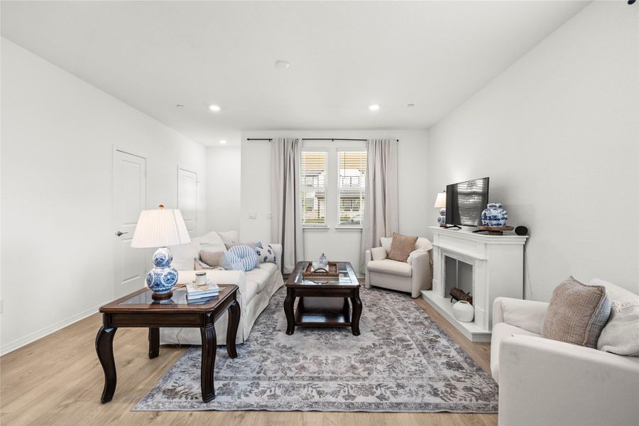 Bright and airy living room with recessed lighting and warm wood flooring.