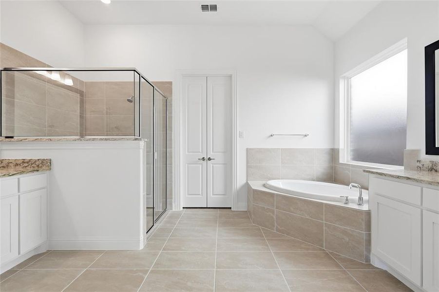 Full bath with vanity, a garden tub, a stall shower, and light tile patterned flooring Full bath with vanity, a garden tub, a stall shower, and light tile patterned flooring