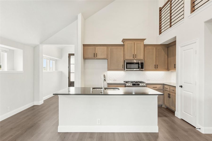 Kitchen with large center island, light wood cabinets, stainless steel appliances, and high vaulted ceiling Kitchen with large center island, light wood cabinets, stainless steel appliances, and high vaulted ceiling