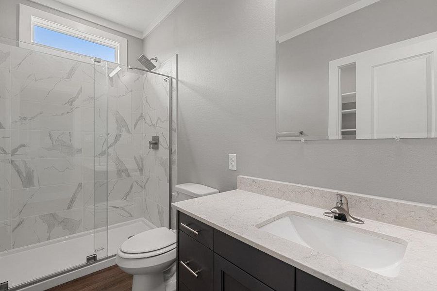 Full bathroom with vanity, a marble finish shower, crown molding, and dark wood-style flooring