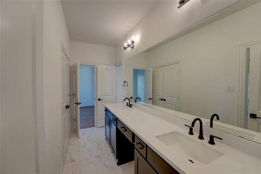 Bathroom with marble finish floor, a sink, and double vanity