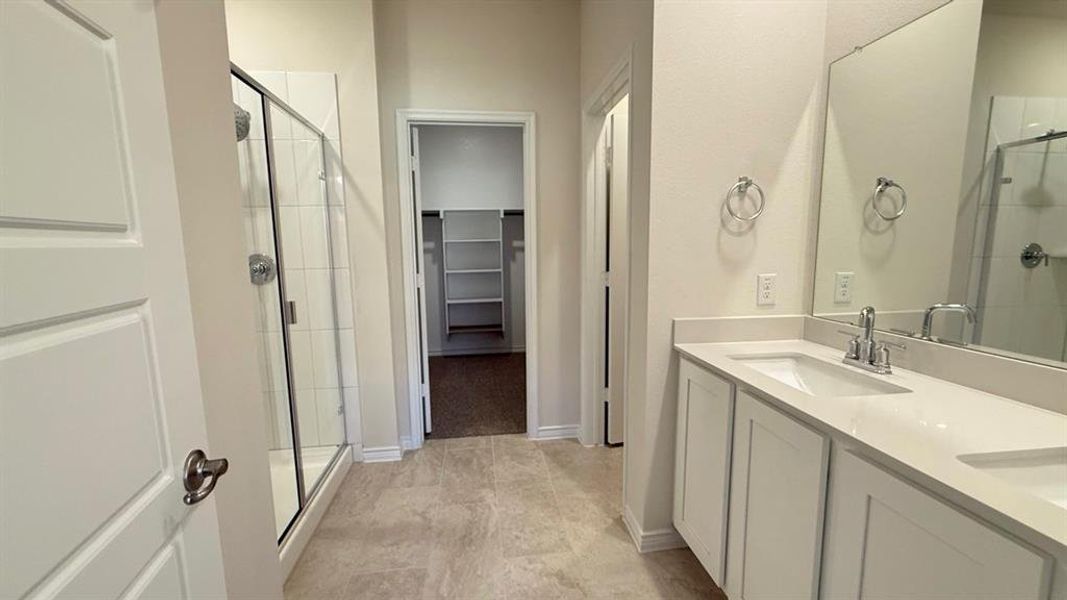 Full bathroom with a shower stall, double vanity, and a walk in closet Full bathroom with a shower stall, double vanity, and a walk in closet