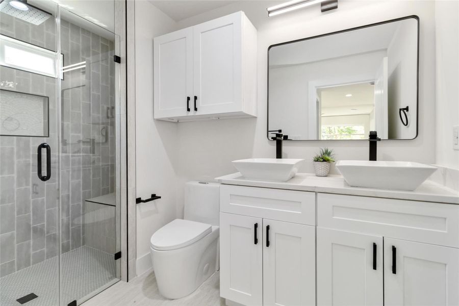 Ensuite featuring sleek toilets with overhead cabinetry and a double vanity for added style and functionality. Ensuite featuring sleek toilets with overhead cabinetry and a double vanity for added style and functionality.