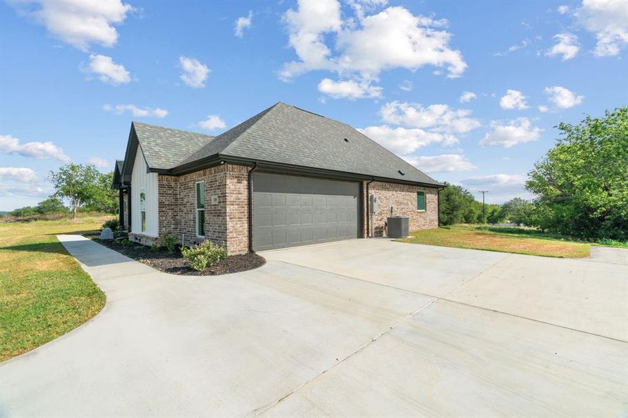 Back of property with brick siding, a chimney, a shingled roof, and a lawn