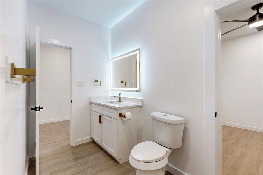 Bathroom with hardwood / wood-style floors, vanity, ceiling fan, and toilet