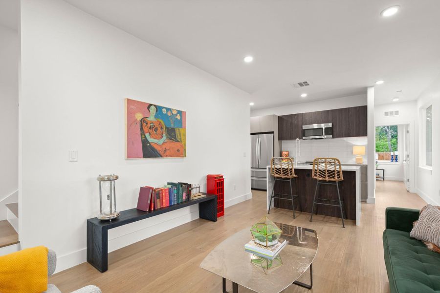 Open-concept living space featuring wood-finish flooring, recessed lighting, and a contemporary kitchen