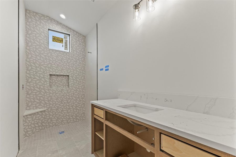 Shower featuring geometric pattern tile, built-in shelving, and a corner bench