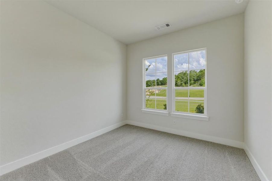 Bright room featuring two large windows, neutral-toned carpeting, white baseboards, and light-colored walls Bright room featuring two large windows, neutral-toned carpeting, white baseboards, and light-colored walls
