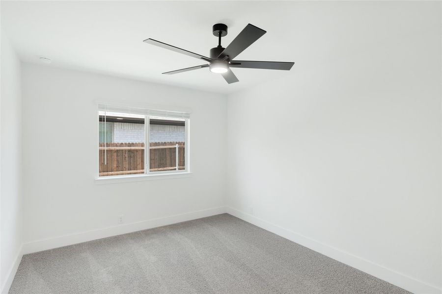 Empty bedroom with gray carpet, white walls, ceiling fan, and single window Empty bedroom with gray carpet, white walls, ceiling fan, and single window