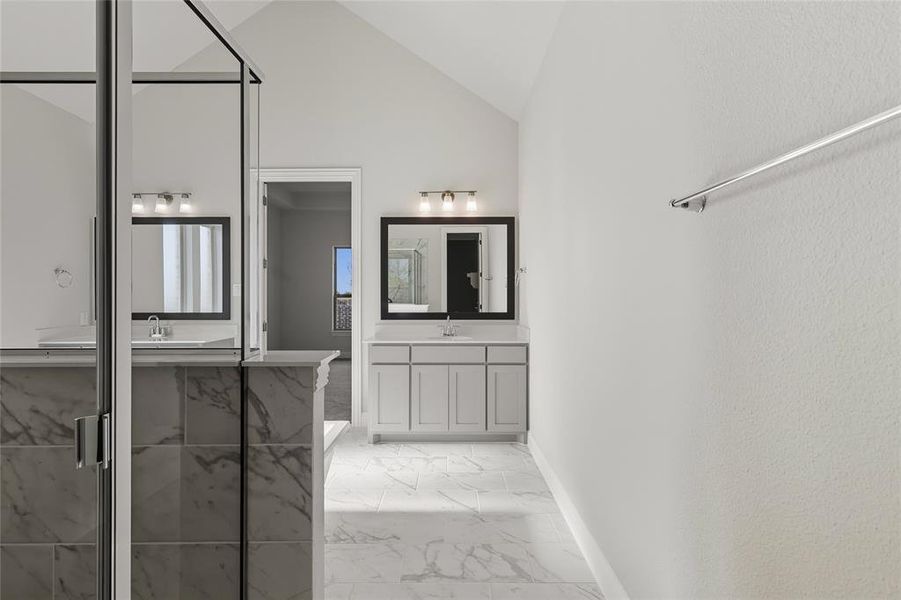 Bathroom with a marble finish shower, vanity, light marble finish floors, and vaulted ceiling Bathroom with a marble finish shower, vanity, light marble finish floors, and vaulted ceiling