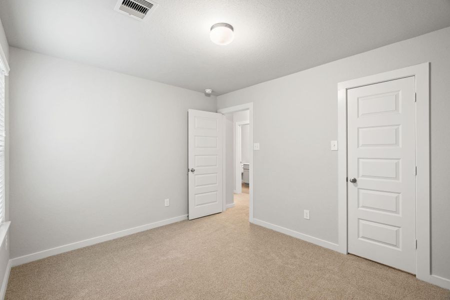 Generously sized secondary bedrooms featuring spacious closets, soft and inviting carpeting underfoot, large windows allowing plenty of natural light, and the added touch of privacy blinds for your personal retreat. Sample photo of completed home with similar floor plan. As-built interior colors and selections may vary.