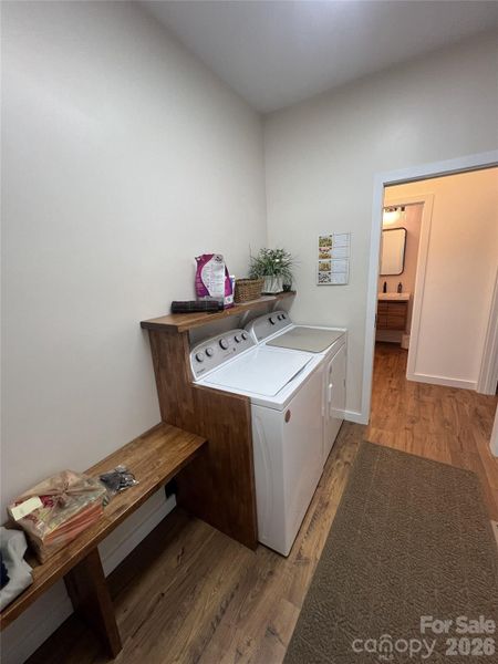 Laundry room with custom seat and shelf. Large storage closet opposite side