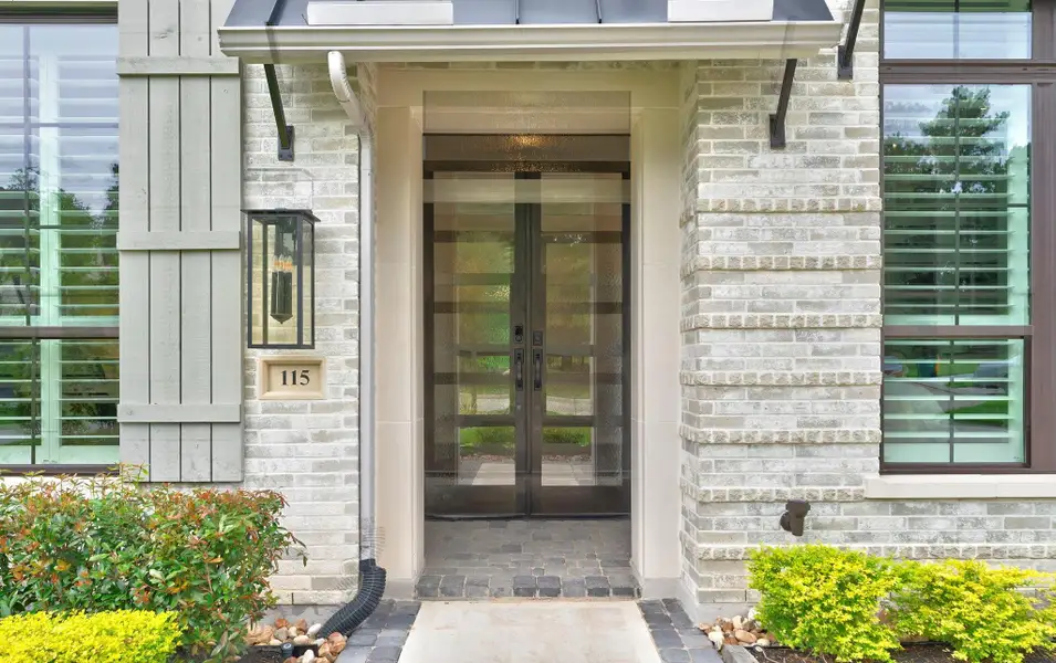 The front entry makes an elegant first impression with double doors, brick detailing, and upgraded glass accents. This close-up view highlights the home’s refined exterior selections and welcoming arrival.