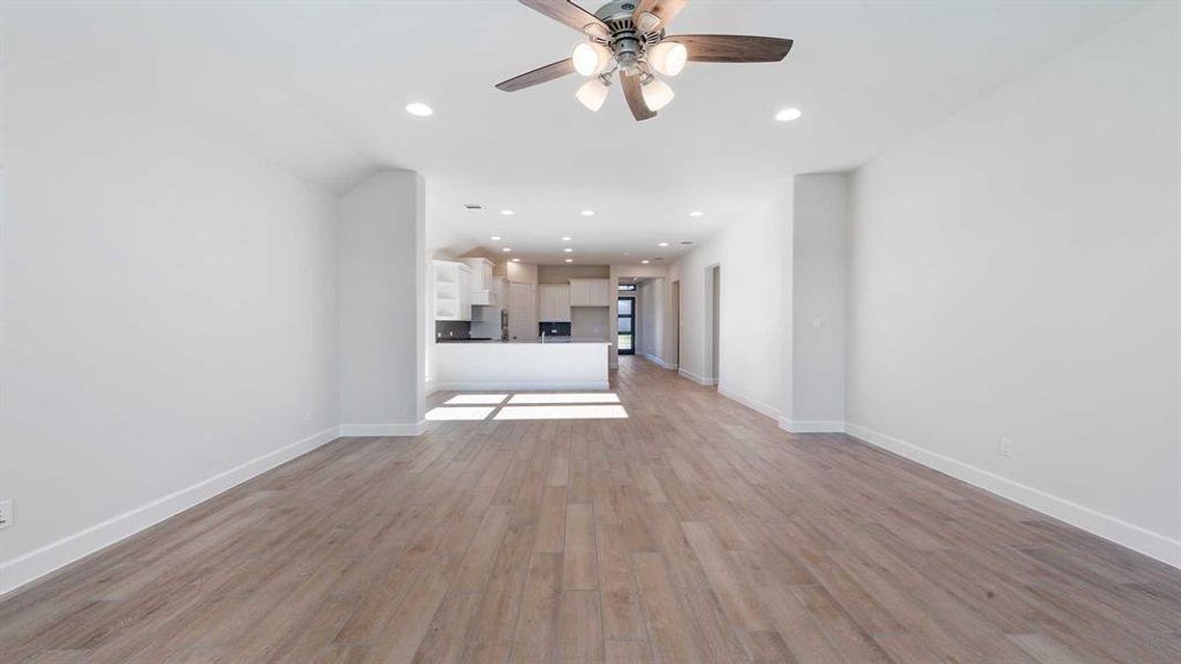 Unfurnished living room featuring ceiling fan and light hardwood / wood-style floors