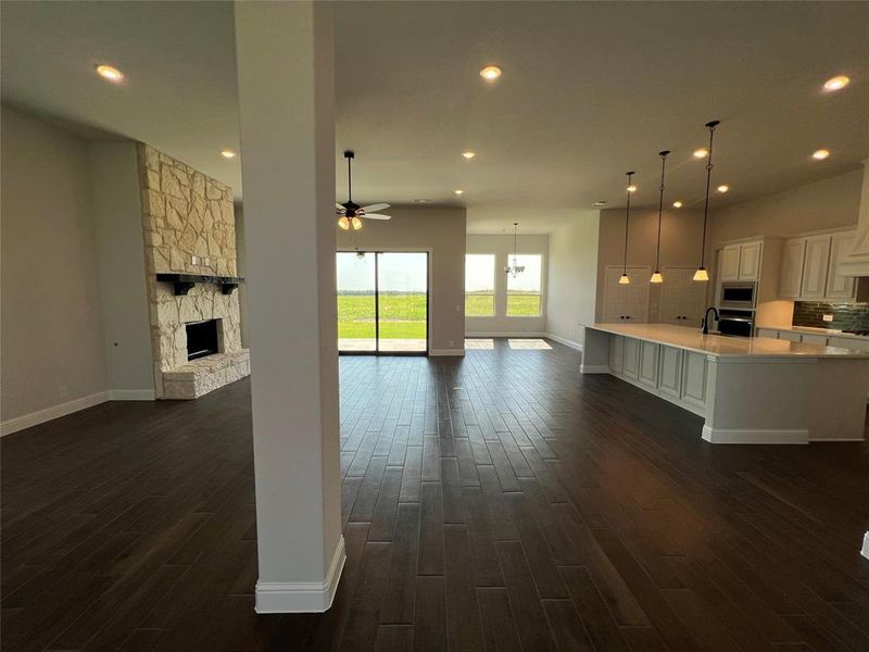 Unfurnished living room featuring a stone fireplace, recessed lighting, dark wood-style floors, and a ceiling fan
