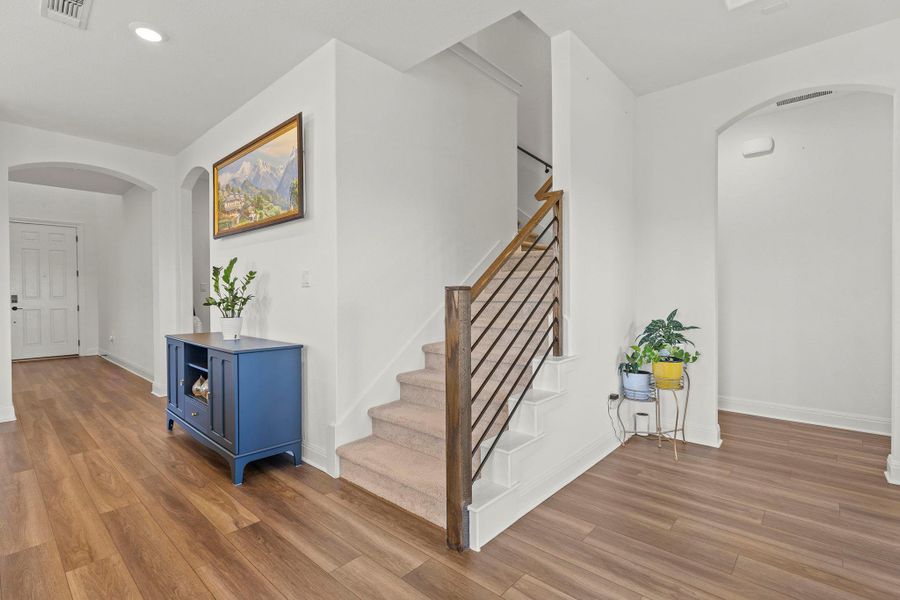Stairway featuring arched walkways, wood finished floors, and recessed lighting
