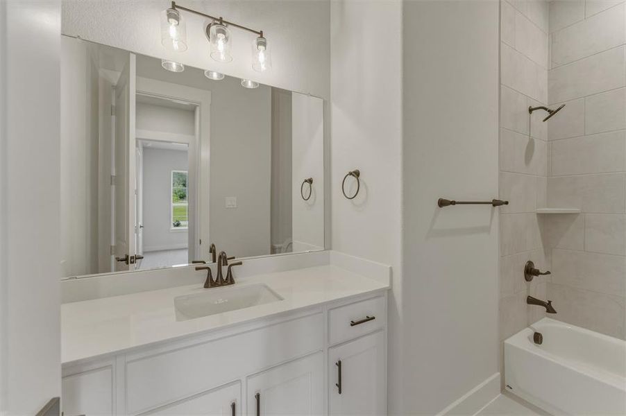 Bathroom featuring a white vanity with an integrated sink, bronze-finish faucet, and coordinating hardware Bathroom featuring a white vanity with an integrated sink, bronze-finish faucet, and coordinating hardware
