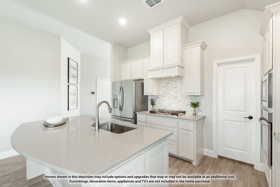 Kitchen with white cabinets, large island with sink, stainless steel appliances, and tile backsplash