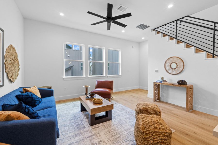 Living room with light wood-type flooring, a ceiling fan, and recessed lighting