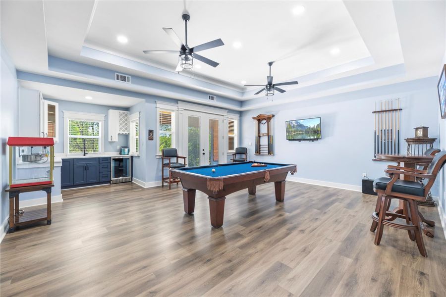 Expansive entertainment lounge with tray ceilings, custom wet bar, and ample space for recreation and gatherings.