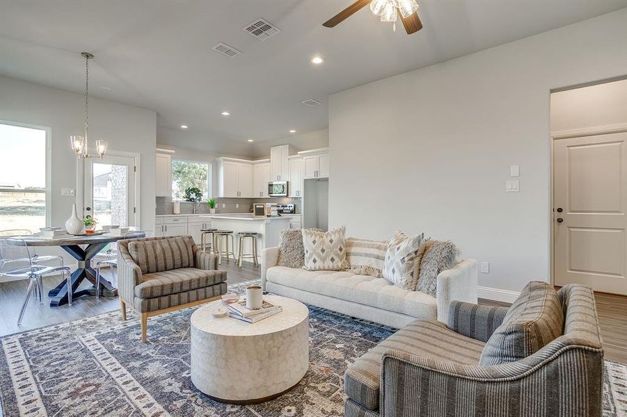 Living room with wood finished floors, recessed lighting, a chandelier, and ceiling fan