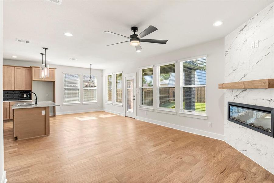Unfurnished living room featuring healthy amount of natural light, ceiling fan, a premium fireplace, light wood-style floors, and recessed lighting
