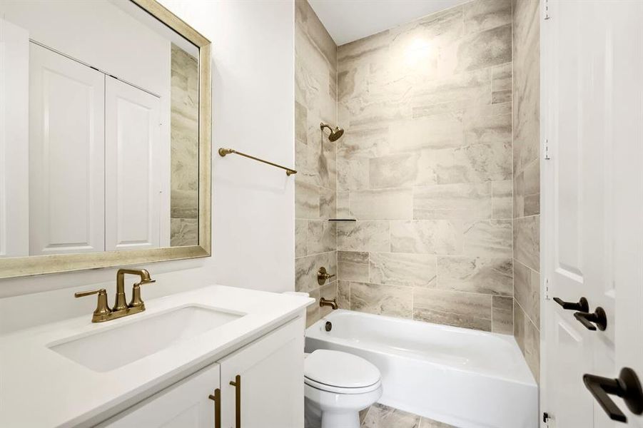 Bathroom featuring a white vanity with integrated sink, brass-finish faucet, and coordinating hardware Bathroom featuring a white vanity with integrated sink, brass-finish faucet, and coordinating hardware