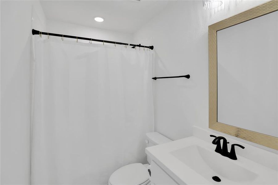 Bathroom featuring a single vanity with a white countertop, rectangular sink, and matte black faucet