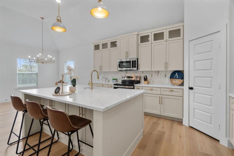 Kitchen with backsplash, hanging light fixtures, stainless steel appliances, lofted ceiling, and light stone countertops