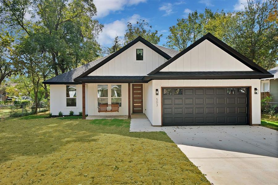 Modern inspired farmhouse with roof with shingles, board and batten siding, concrete driveway, and a garage
