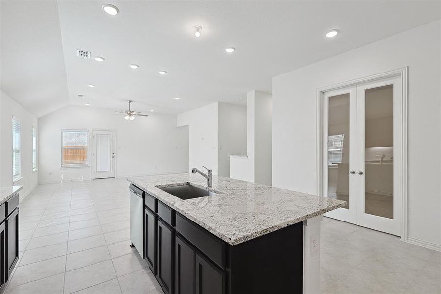 Kitchen with ceiling fan, a center island with sink, french doors, and sink