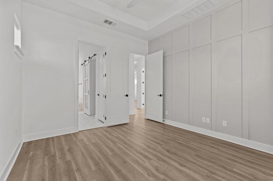 Unfurnished bedroom with a decorative wall, light wood-type flooring, and ceiling fan