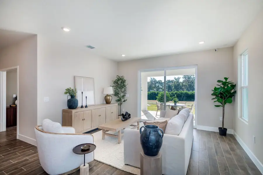 A bright and inviting great room featuring modern finishes, warm natural light, and seamless indoor-outdoor living with large sliding doors that open to the covered lanai. A bright and inviting great room featuring modern finishes, warm natural light, and seamless indoor-outdoor living with large sliding doors that open to the covered lanai.