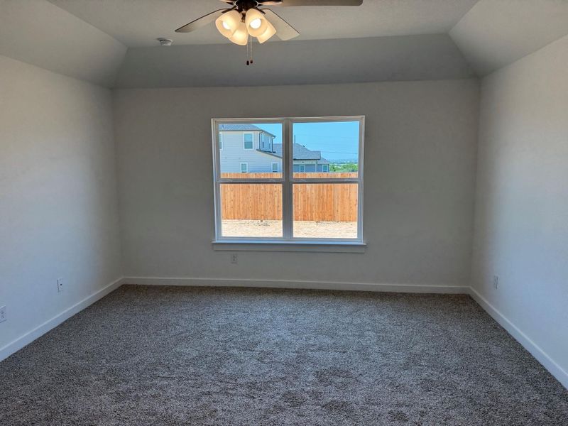 Empty room featuring lofted ceiling, carpet floors, and a ceiling fan Empty room featuring lofted ceiling, carpet floors, and a ceiling fan