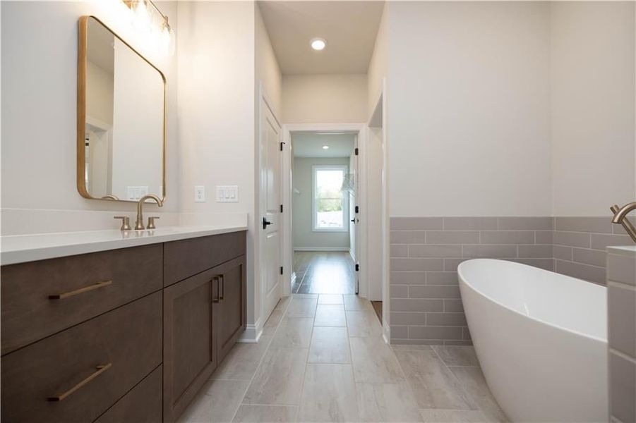 Bathroom with vanity, a tub to relax in, and tile walls