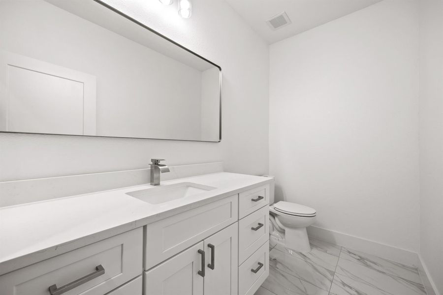 Half bathroom on main floor featuring vanity and light tile flooring