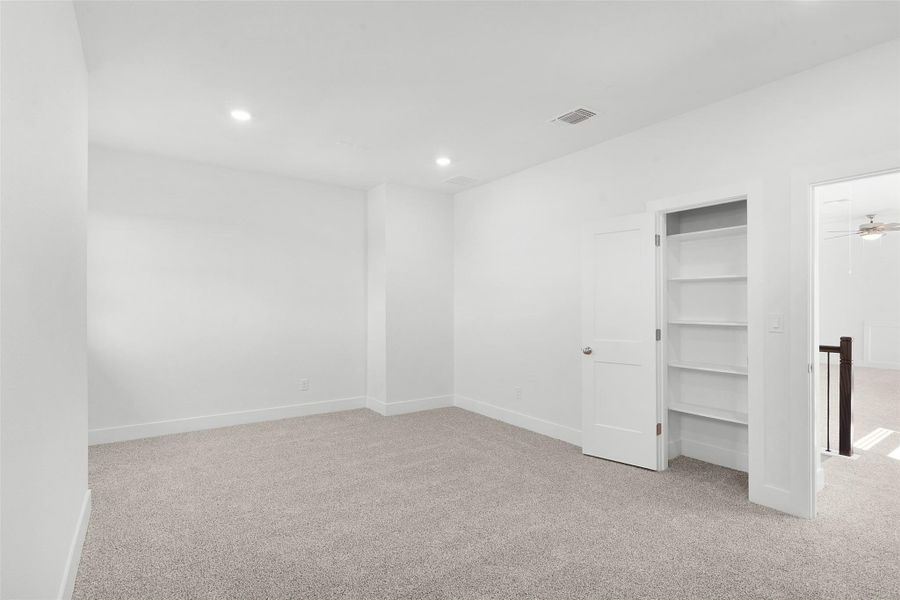 A well-proportioned room with plush carpeting and functional built-in shelving.