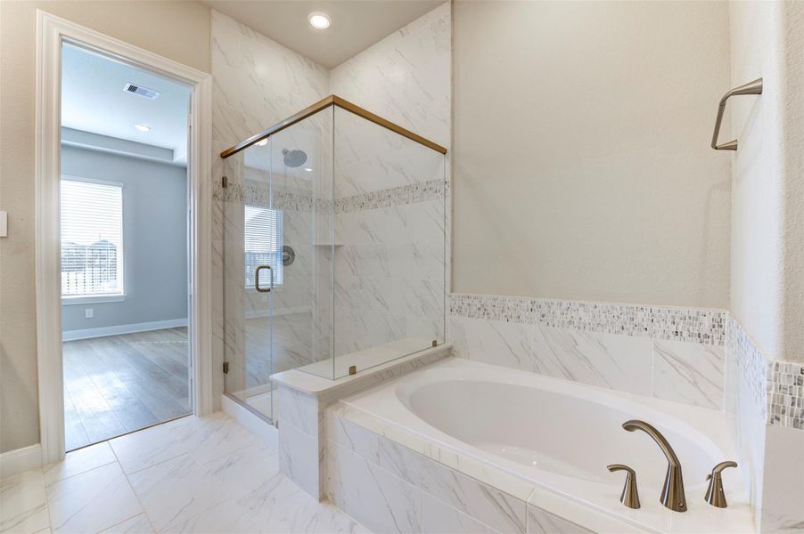 Primary bathroom with soaking tub, glass walk-in shower, and elegant tile finishes.