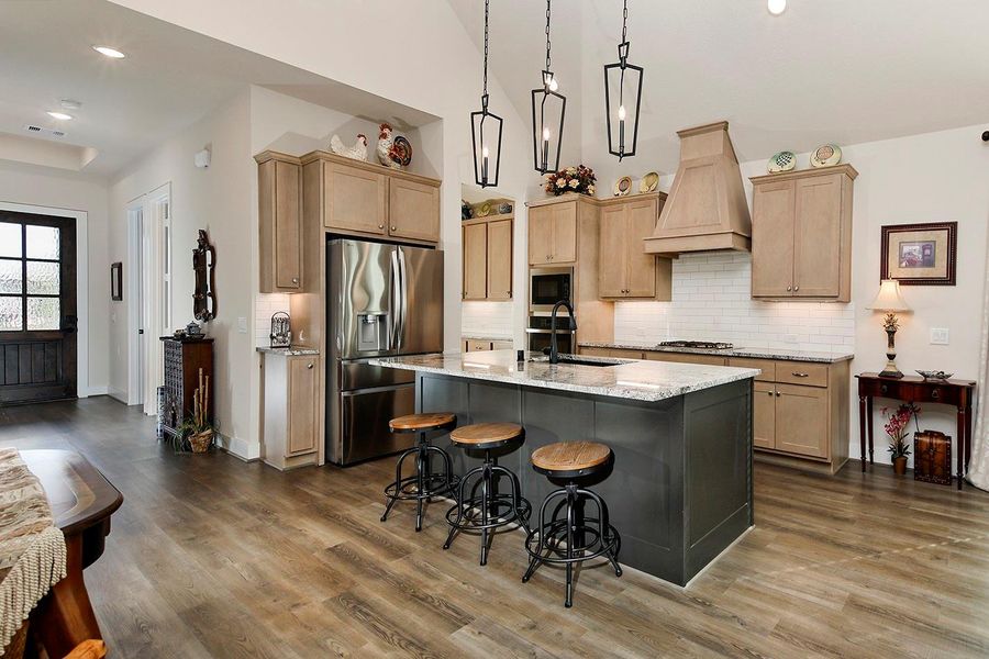 Lovely kitchen cabinetry w matching wood vent hood; island accented and lovely pendant lighting adds charm and offers casual seating/dining Lovely kitchen cabinetry w matching wood vent hood; island accented and lovely pendant lighting adds charm and offers casual seating/dining